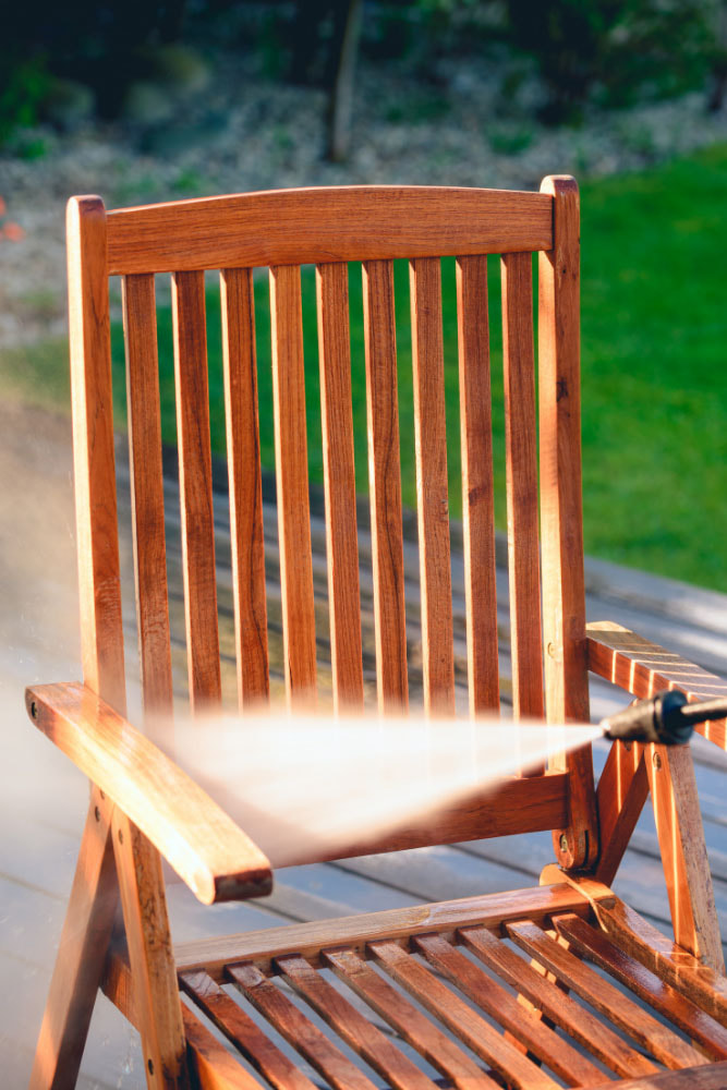 Cleaning off wooden chair outdoors with water