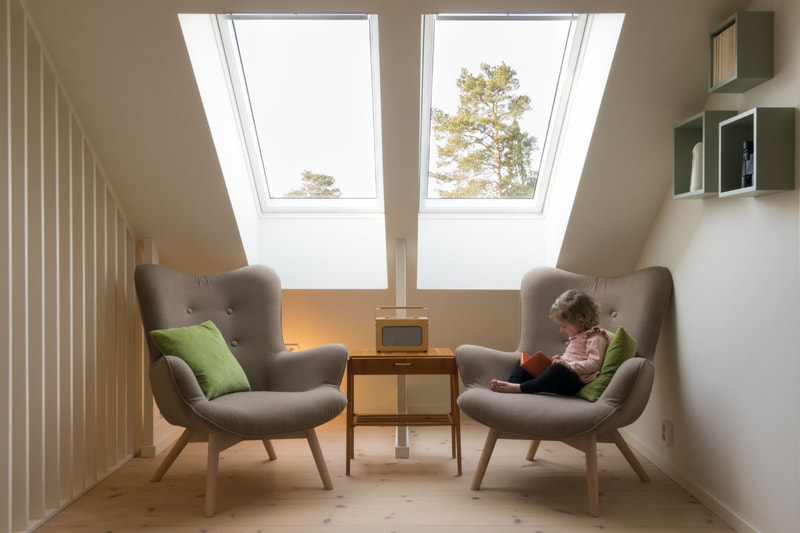 2 chairs beneath 2 large skylights with child reading a book