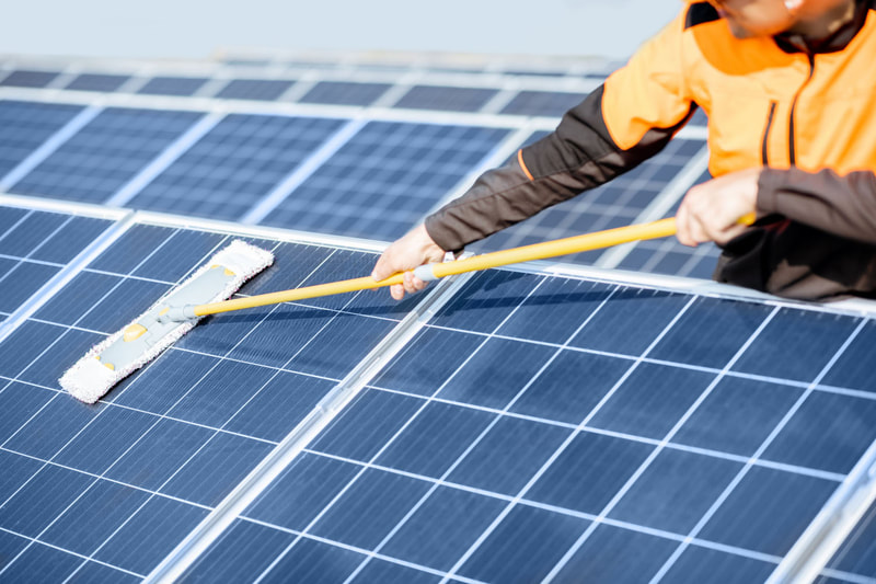 Worker holding squeegee to clean photovoltaic cells